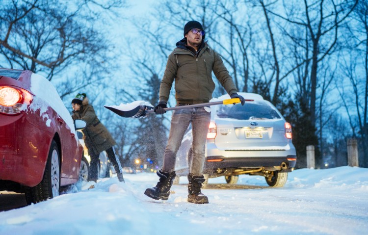 Joshua Locke of Portland shovels out his wife's vehicle from the parking area in Deering Oaks on Monday morning.