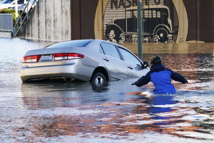 Kenneth Warner races into the water to help rescue the driver of a car that went into the flooded Nooksack River on Nov. 16 in Ferndale, Wash. The Pacific Northwest is getting record rainfall, while Denver and the Rockies still haven't seen their first significant snowfall of the season.
