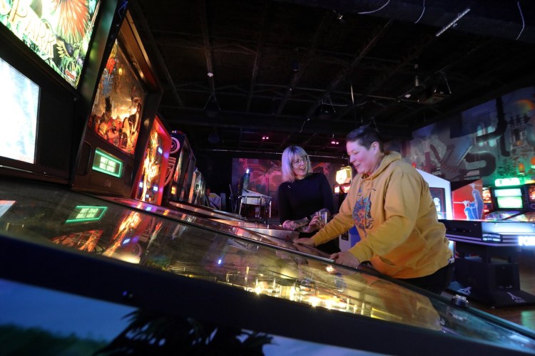  Rebeka Sobodacha, left, watches while Caitlin Flynn plays Scared Stiff, an Elvira-Themed pinball machine at Arcadia.